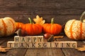 Happy Thanksgiving greeting against rustic wood with pumpkins and autumn leaves Royalty Free Stock Photo