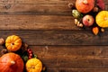 Happy Thanksgiving holiday banner design. Ripe orange pumpkins, apples, red berries in corners on dark wooden table Royalty Free Stock Photo