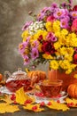 happy thanksgiving still life. autumn flowers Roses, chrysanthemums, asters in a pumpkin vase and tea in a glass on the table Royalty Free Stock Photo