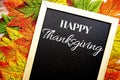 Happy Thanksgiving text on blackboard decorate with maple leaves and pumpkin on wooden background