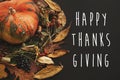 Happy Thanksgiving text on pumpkin in autumn leaves wreath, berries, nuts, acorns, flowers,herbs on dark background, isolated. Se Royalty Free Stock Photo