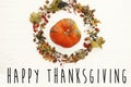 Happy Thanksgiving text on pumpkin in beautiful fall leaves wreath with berries,nuts,acorns, herbs on rustic white background top Royalty Free Stock Photo