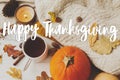 Happy Thanksgiving text sign on warm tea, pumpkins, cozy knitted sweaters, autumn leaves and candle. Seasons greetings. Happy Royalty Free Stock Photo