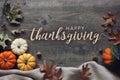 Happy Thanksgiving typography with pumpkins and leaves over dark wood background