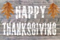 Happy Thanksgiving written on wooden board background with two leaves Royalty Free Stock Photo