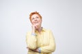 Happy thinking casual woman with red hairstyle dreaming looking up. She is planning her future.