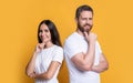 Happy thinking couple stroking chins studio. Smiling couple thinking isolated on yellow