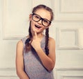 Happy thinking kid girl in fashion glasses with excited emotional face looking on studio background. Toned closeup portrait Royalty Free Stock Photo