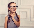 Happy thinking kid girl in fashion glasses with excited emotional face looking on studio background. Closeup toned portrait Royalty Free Stock Photo