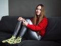 Happy adorable adult woman sitting on grey sofa