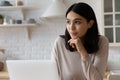 Happy thoughtful Asian student girl sitting at laptop Royalty Free Stock Photo