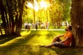 A happy thoughtful dreamer man is sitting on green grass in park