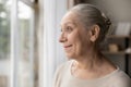 Happy thoughtful mature 70s woman looking out of window Royalty Free Stock Photo