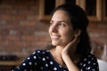 Happy thoughtful millennial Latin woman enjoying break at home