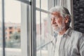 Happy thoughtful older 70s man looking out of window away with hope, thinking of good health, retirement, insurance benefits, Royalty Free Stock Photo