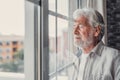 Happy thoughtful older 70s man looking out of window away with hope, thinking of good health, retirement, insurance benefits, Royalty Free Stock Photo
