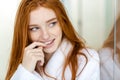 Happy thoughtful redhead woman in bathrobe