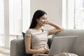 Happy thoughtful young Asian freelancer woman working at home