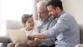 Happy three generation family grandfather father and grandson using laptop Royalty Free Stock Photo