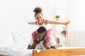 Cheerful african girl playing with father, flying like plane