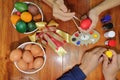 Happy time of family members are painting colorful eggs with a paintbrush and palette for preparing happy Easter day. Royalty Free Stock Photo