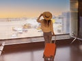 Asian young tourist woman holding the luggage and watching the flight and sunlight through window in Airport terminal