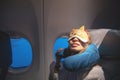 Tired young woman comfortably sleeping with mask and pillow in airplane. Sophisticated traveler concept