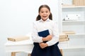 Happy to enter into first form. Girl child holds book stand near table white background. Schoolgirl enjoy studying and