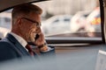 So happy to hear you. Side view of mature businessman sitting in the car and talking by the phone Royalty Free Stock Photo