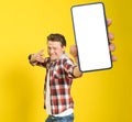 Happy to win handsome man pointing at smartphone with white empty screen, wearing red plaid shirt and jeans cellphone Royalty Free Stock Photo