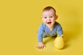 Happy toddler baby at the age of six months plays laughing on studio yellow background. Funny child boy crawling and smiling, copy Royalty Free Stock Photo