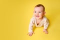 Happy toddler baby at the age of six months plays laughing on studio yellow background. Funny child boy crawling and smiling, copy Royalty Free Stock Photo