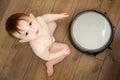 Happy toddler baby boy is playing with a robot vacuum cleaner on the f Royalty Free Stock Photo