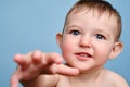 Happy toddler baby boy reaching out with his hand, studio blue backgr Royalty Free Stock Photo