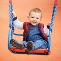 Happy toddler baby boy rides on a swing. Smiling child swinging on the Royalty Free Stock Photo