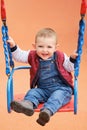 Happy toddler baby boy rides on a swing. Smiling child swinging on the Royalty Free Stock Photo