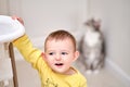 Happy toddler baby boy stands holding onto a children\'s high chair in th Royalty Free Stock Photo