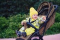 Happy toddler baby boy in yellow overalls sits in a stroller. A child in wa Royalty Free Stock Photo