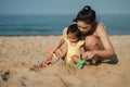 happy toddler baby girl playing sand toy with mother on the sea beach Royalty Free Stock Photo