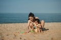 happy toddler baby girl playing sand toy with mother on the sea beach Royalty Free Stock Photo