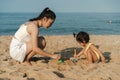 happy toddler baby girl playing sand toy with mother on the sea beach Royalty Free Stock Photo