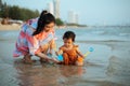 happy toddler baby girl playing toy and water with her mother on sea beach Royalty Free Stock Photo