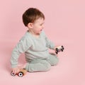 Happy toddler baby is playing with a toy car against a pink background Royalty Free Stock Photo