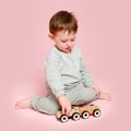 Happy toddler baby is playing with a toy car against a pink background Royalty Free Stock Photo