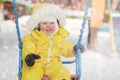 Happy toddler baby rides on a swing on a winter playground. Baby boy Royalty Free Stock Photo