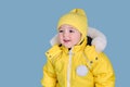 Happy toddler baby in winter clothes snowsuit Kisu on studio blue bac
