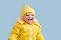 Happy toddler baby in winter clothes snowsuit on studio blue backgrou