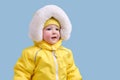 Happy toddler baby in winter clothes snowsuit on studio blue backgrou Royalty Free Stock Photo