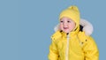 Happy toddler baby in winter clothes snowsuit on studio blue backgrou Royalty Free Stock Photo