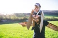 Happy toddler boy and father playing with wings outside in spring nature. Royalty Free Stock Photo